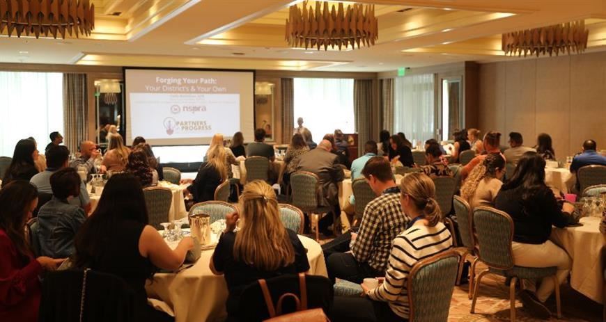 presenter at a conference in a full ballroom